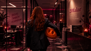 Mulher ruiva em ambiente corporativo com estética de Halloween, segurando uma abóbora, representando criatividade, posicionamento e comunicação profissional nas redes sociais.